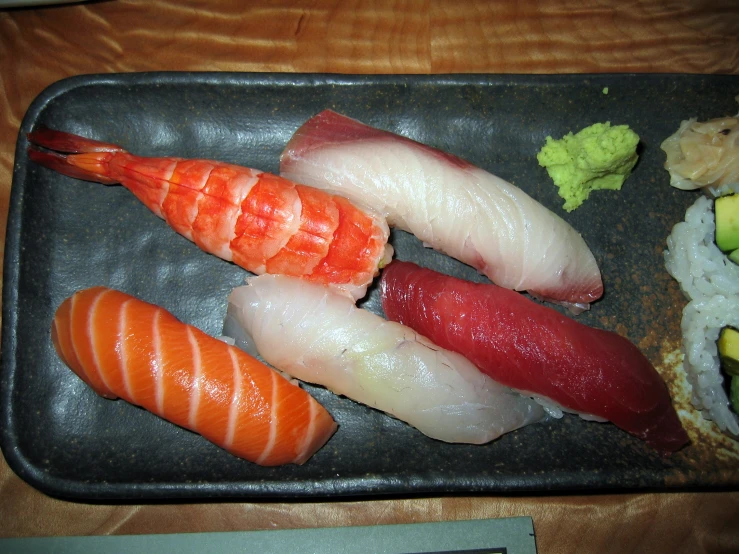 a sushi tray on a table is shown with shrimp and various vegetables