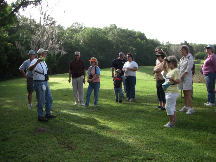 group of adults standing in grassy field with trees