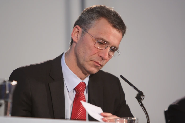 a man in suit and tie holding up a piece of paper