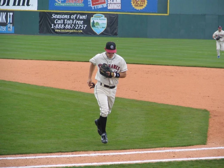 baseball player wearing catchers mitt in grassy baseball field