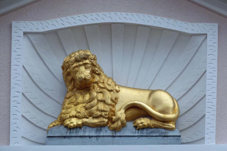 a gold lion sculpture sitting on top of a wooden shelf