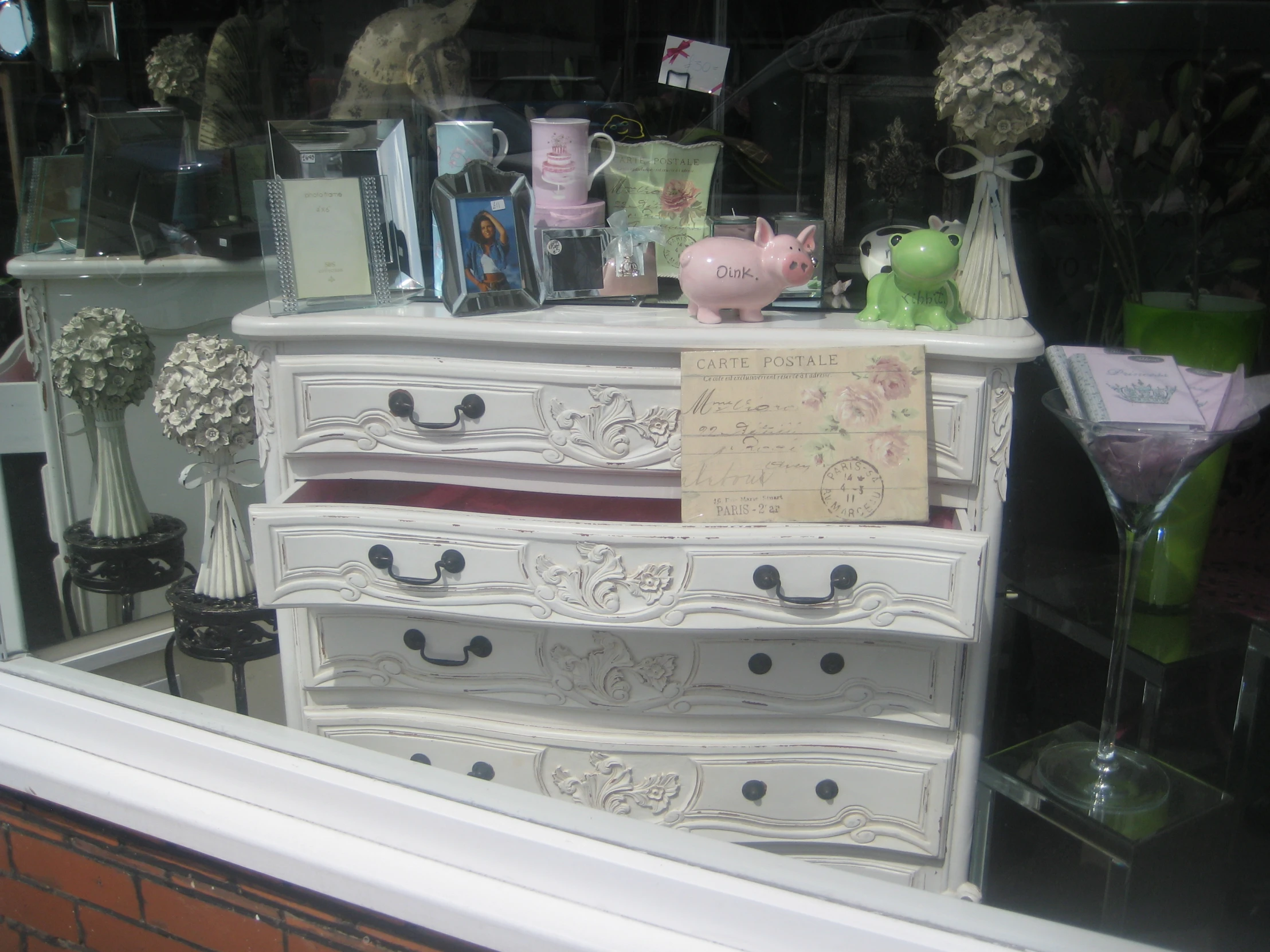 a dresser with glass vases and a pink pig in it