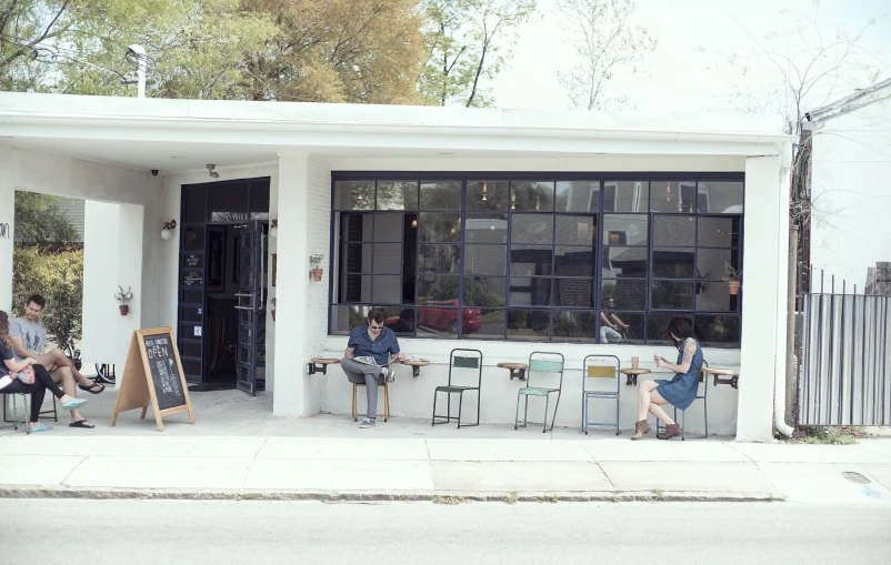 group of people sitting at a restaurant with chairs outside