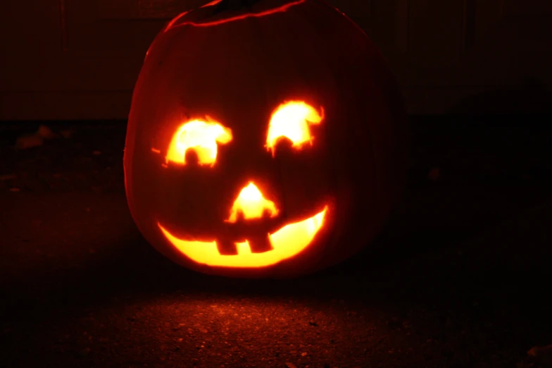 a lighted pumpkin sits in a darkened area