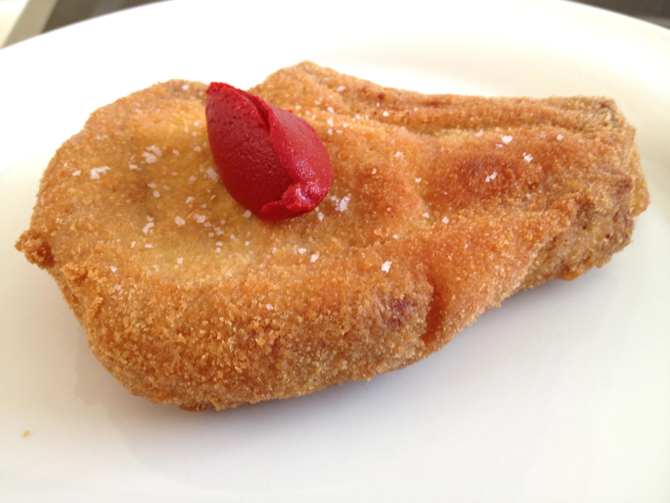 a pastry on a white plate that has a red jelly in it