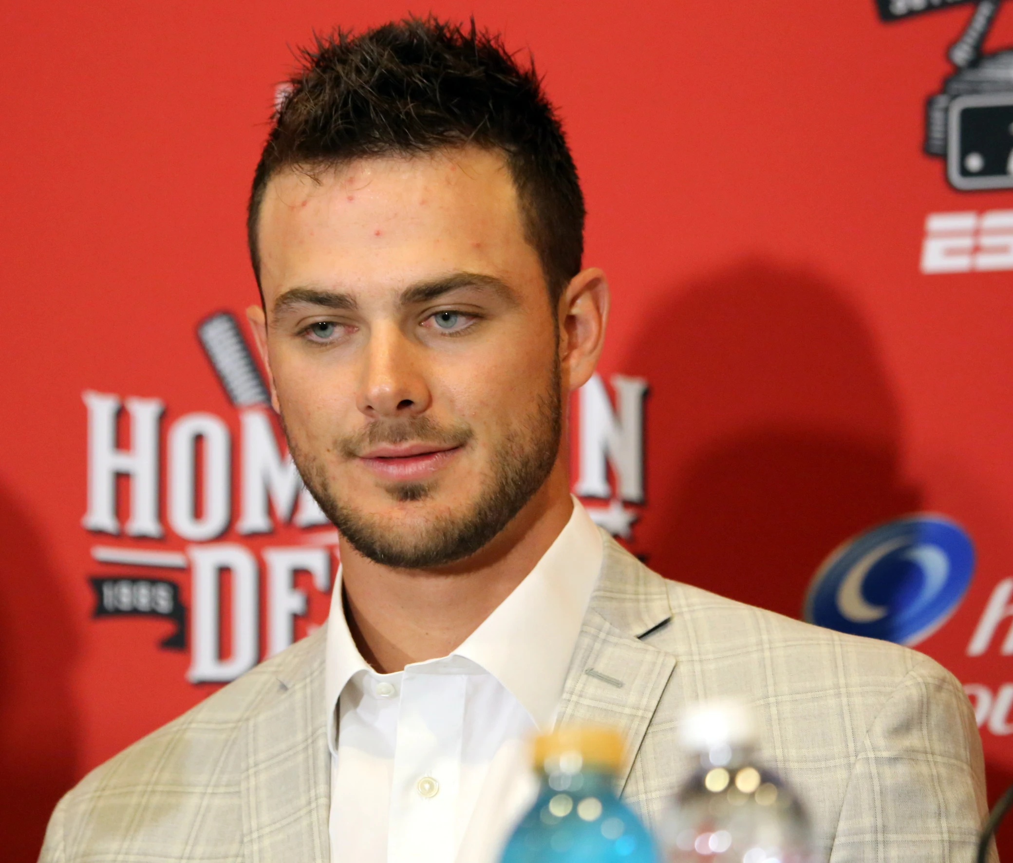 a man standing in front of a red carpet holding a bottle