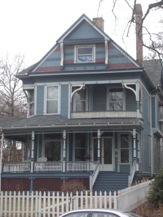 an old, two - story blue house is parked by the picket fence