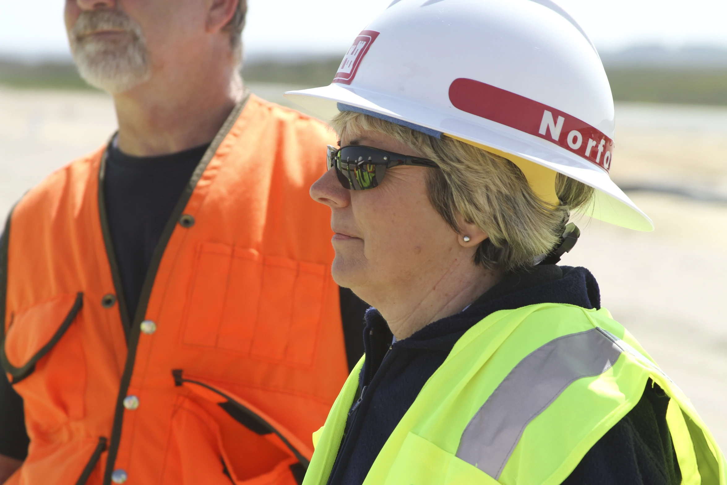 a woman in a hard hat standing next to another man