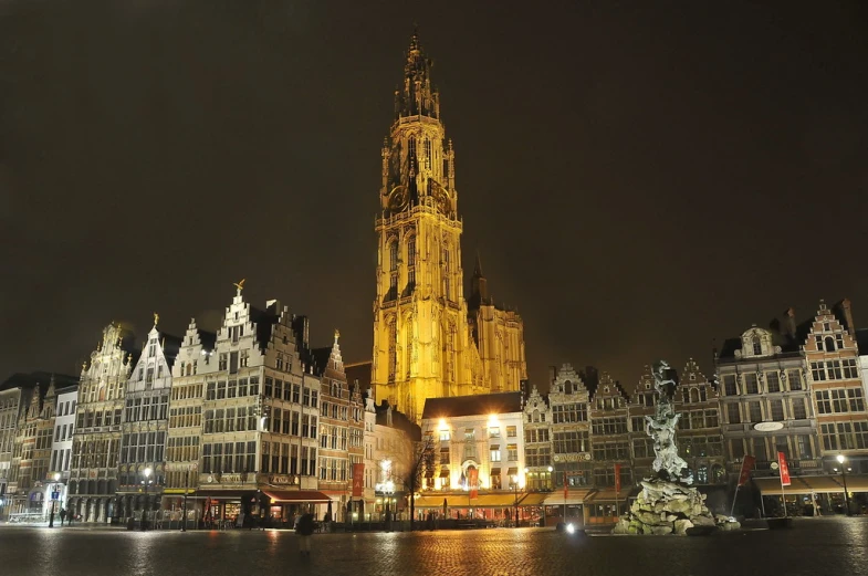 the tall tower is illuminated on the buildings by water