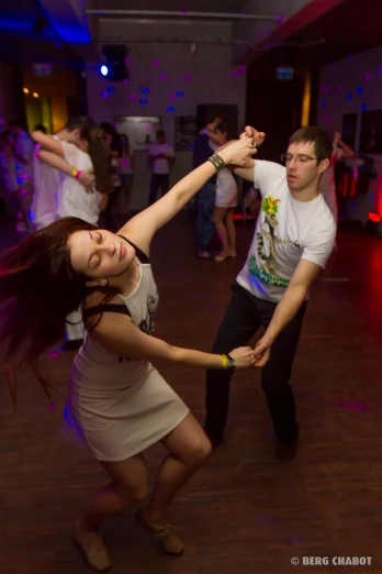 people dance and smile on a hardwood floor at a party