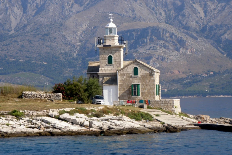 a church sits on a rock in front of mountains