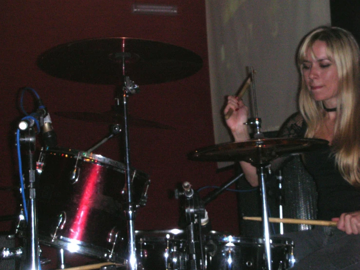 a young lady playing drums in a room