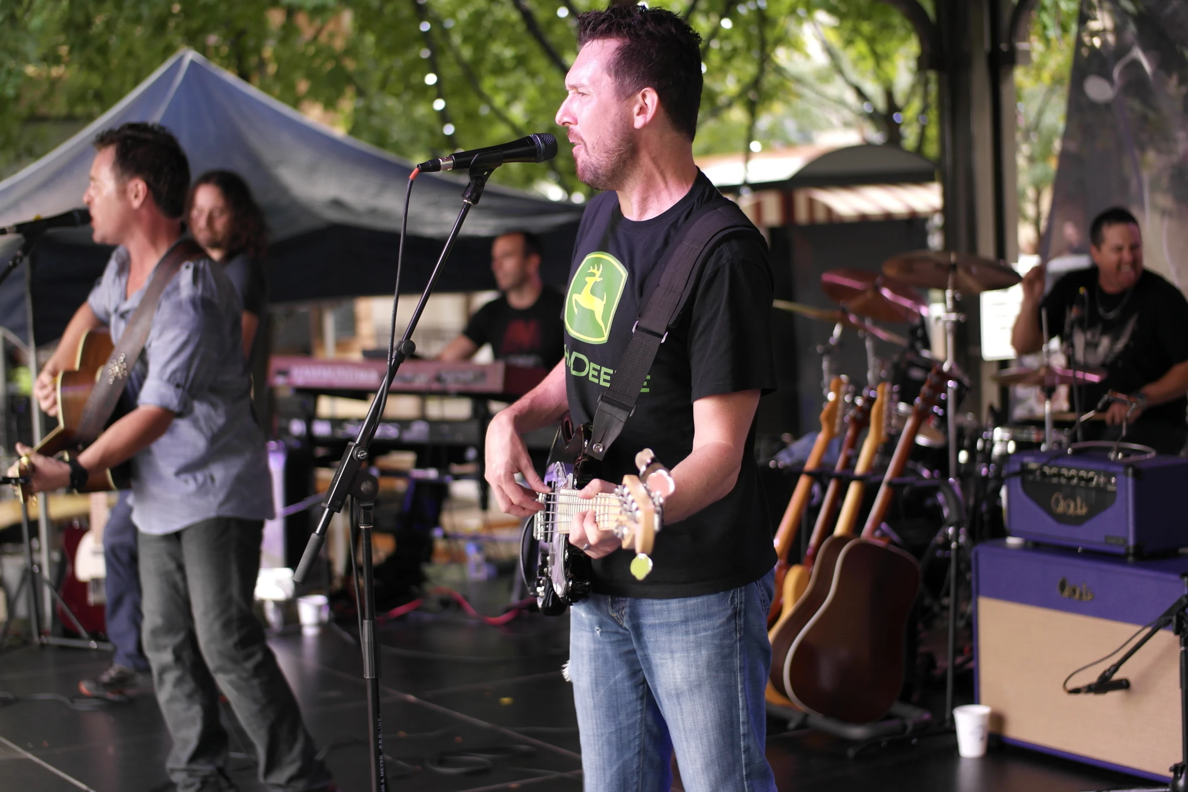 a man standing on stage singing with two other men playing guitars