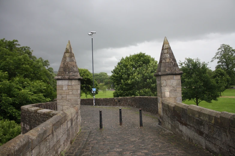 a stone wall leading to two towers on a cloudy day