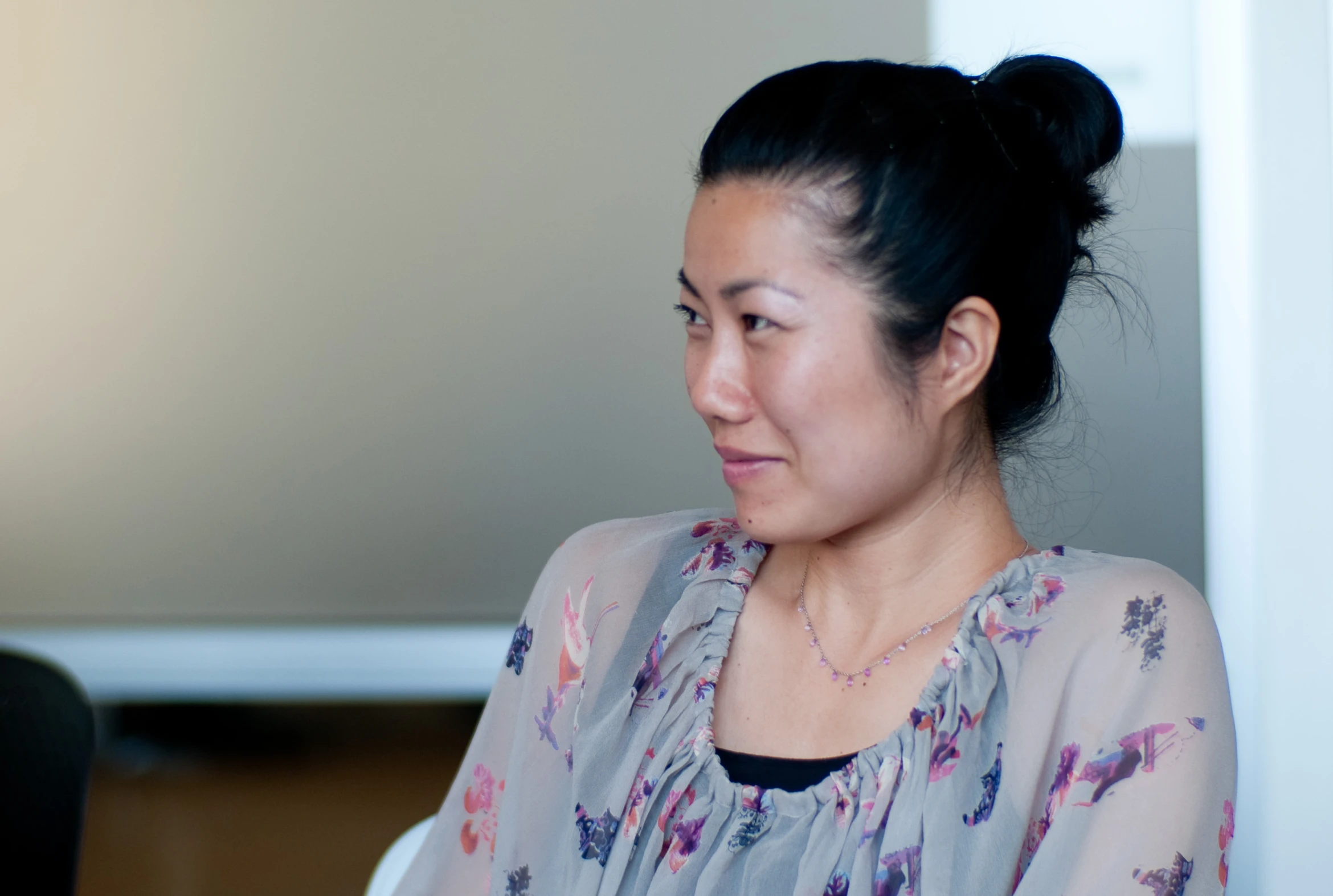 a woman with a necklace on sitting down looking at soing