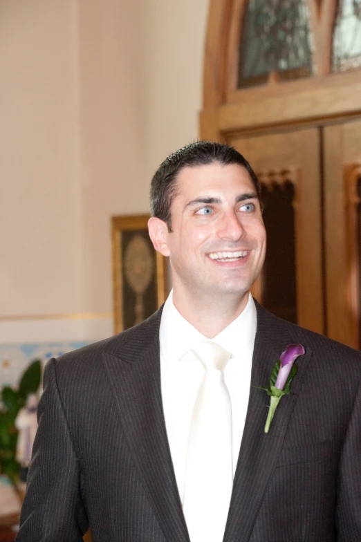 a man wearing a white shirt and black suit and a flower