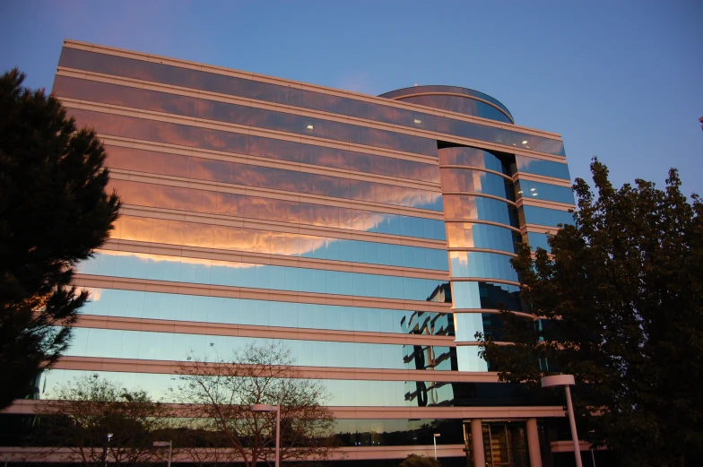 a large glass building that has a sky background behind it