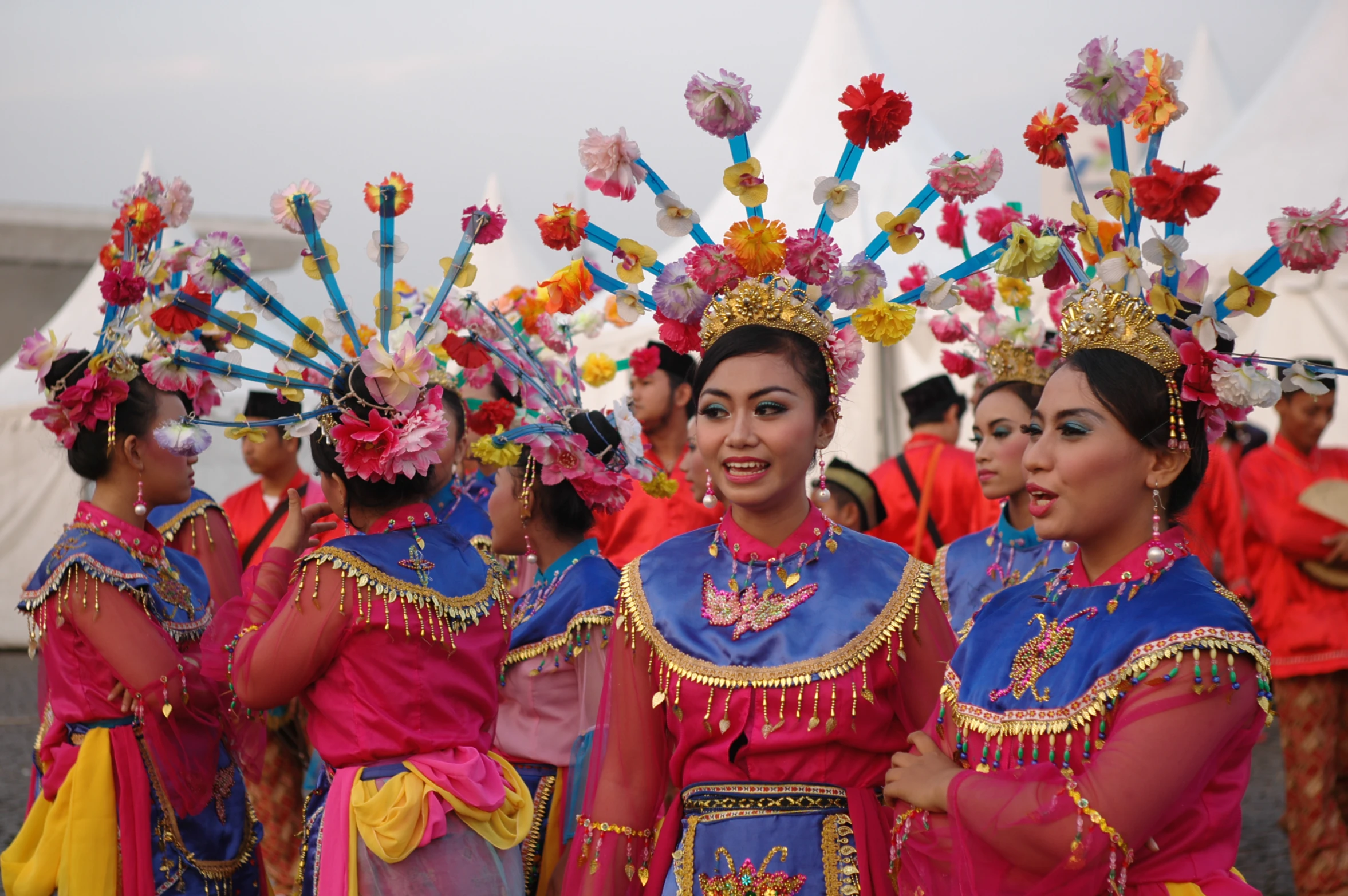 a group of women dressed in bright colors wearing fancy headdresses