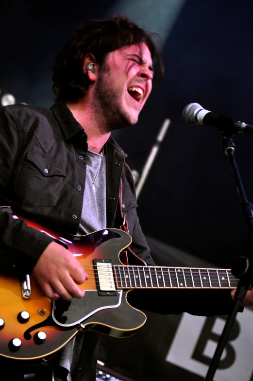 a man with an electric guitar smiling and laughing