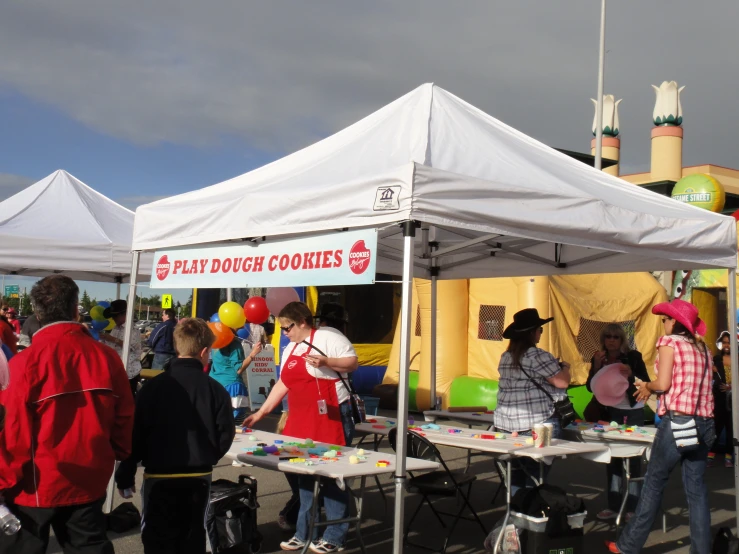 there are several people at a booth selling cookies