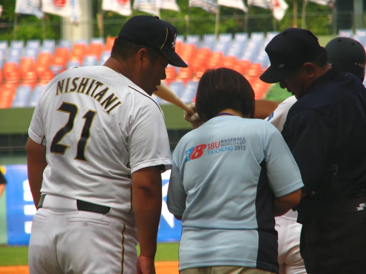 baseball players wearing white uniforms standing around a coach