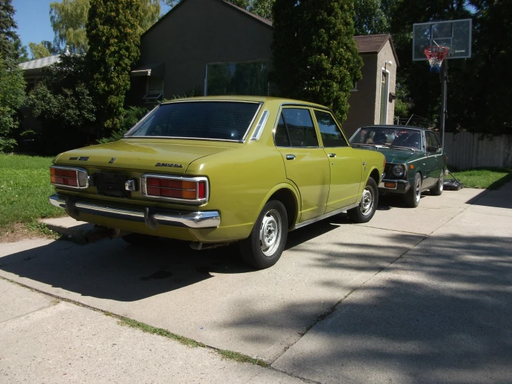 an old yellow truck parked next to another one in front of a house