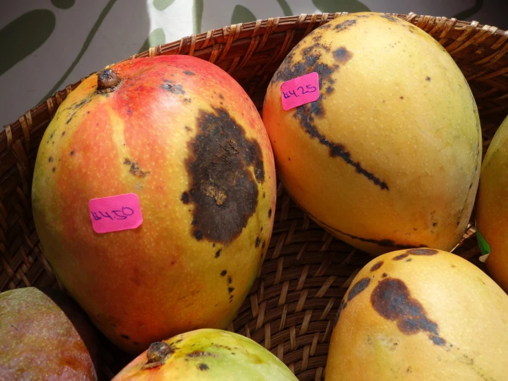 a bunch of yellow and orange fruits in a wicker basket