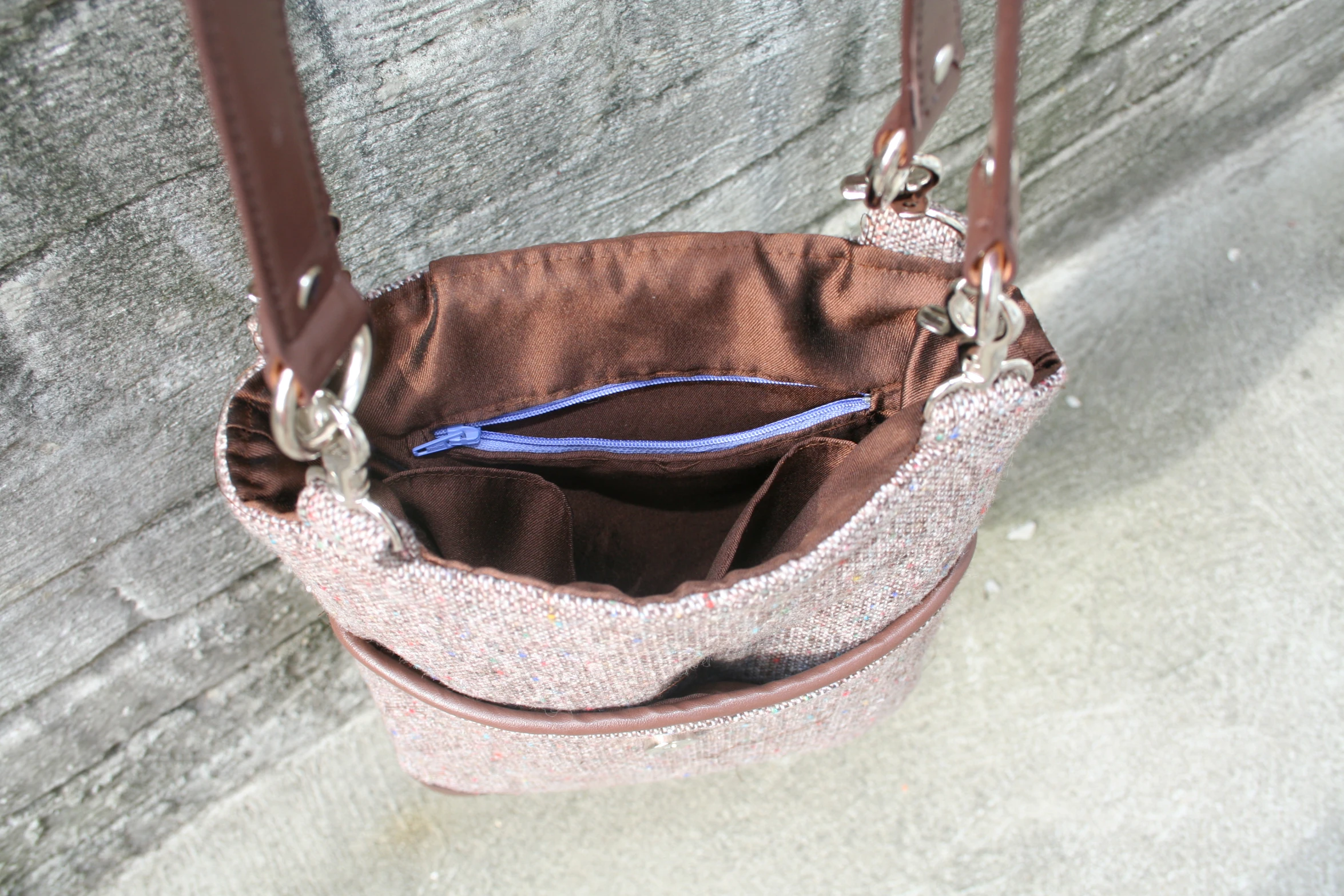 a pink and brown purse laying on top of cement