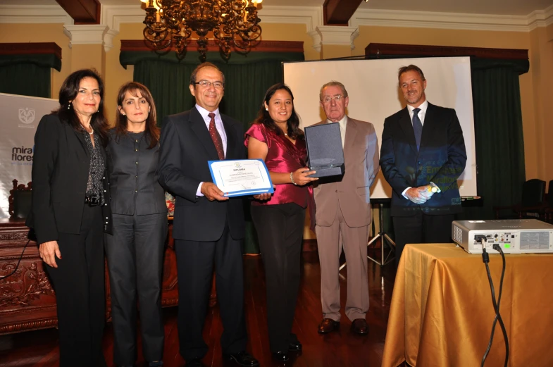 the group of people in suits and ties hold up an award plaque