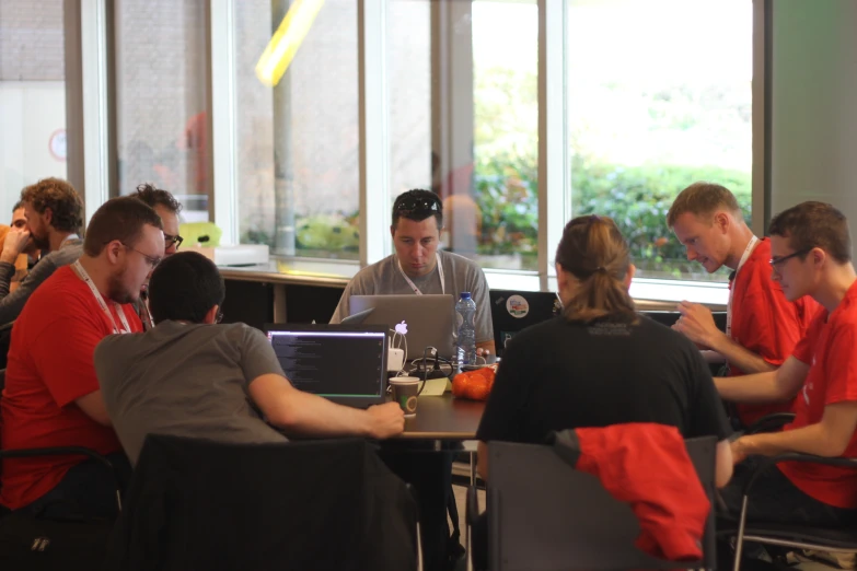 a group of people sitting at a restaurant table looking at laptops