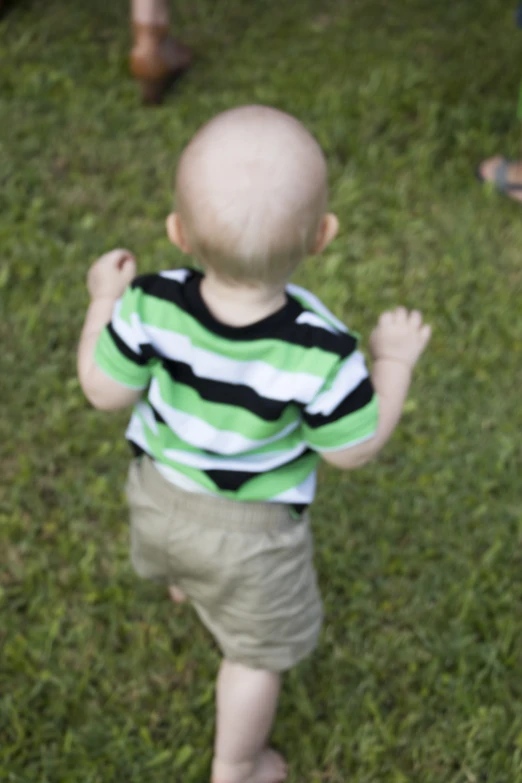 a small child in shorts and a shirt stands in the grass