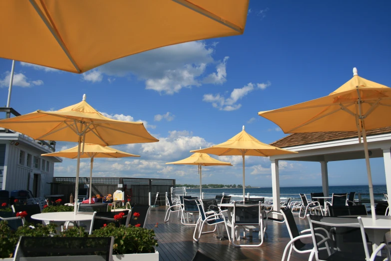 some tables chairs and yellow umbrellas on a wooden deck