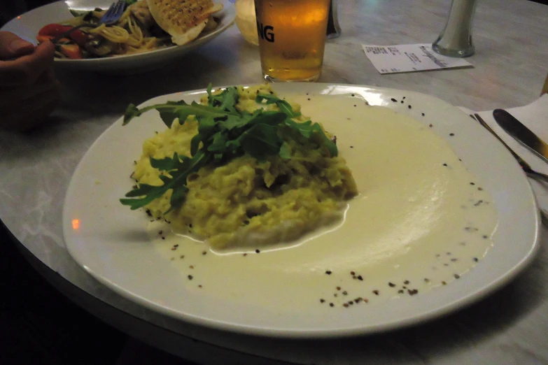 a meal sits on a white plate on a table with a glass