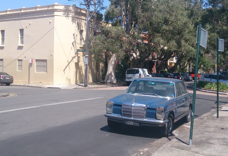 an old blue car is parked near a light pole