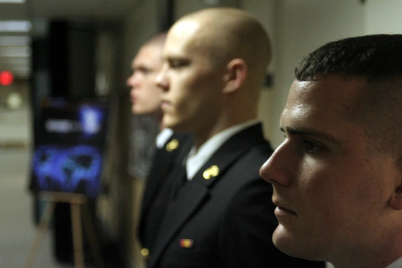 three men dressed in uniforms looking back at soing on the screen