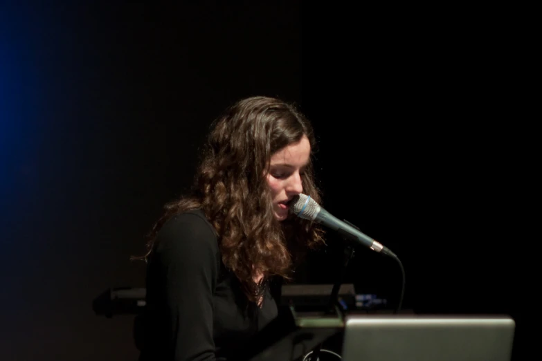 woman at computer using microphone in dark space