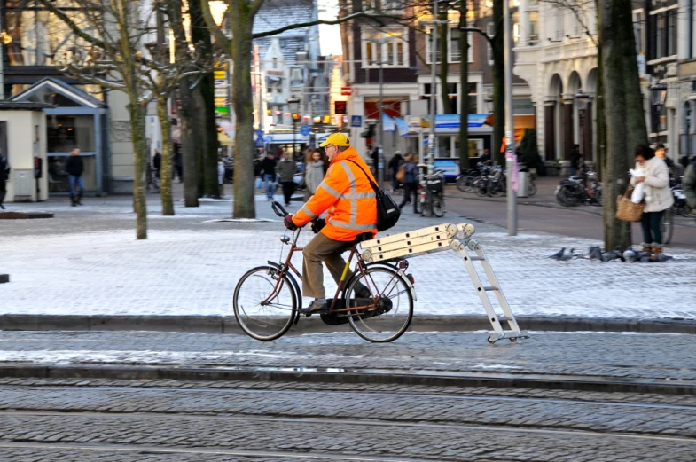 the man is crossing a city street with his bicycle