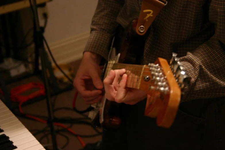 someone plays guitar in the living room while standing by the piano