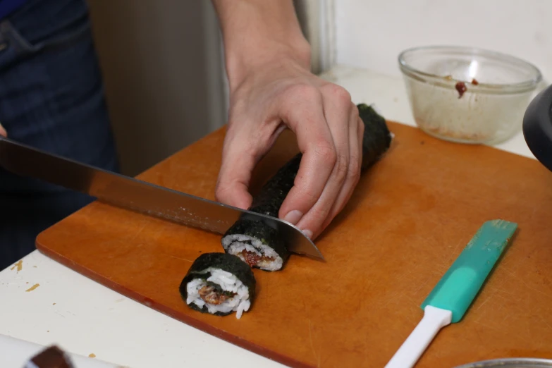 someone using a knife to slice up a sushi