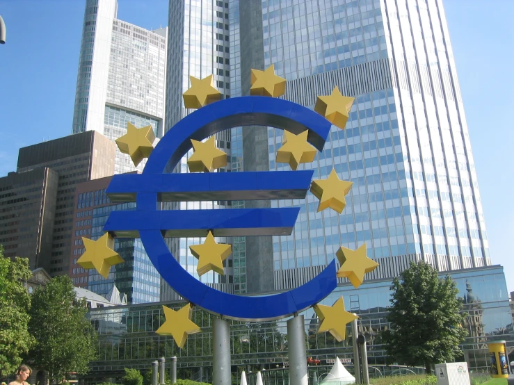 large sculpture with euro sign surrounded by golden stars in city