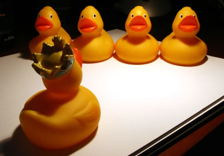 several rubber ducks on a desk with a gold crown