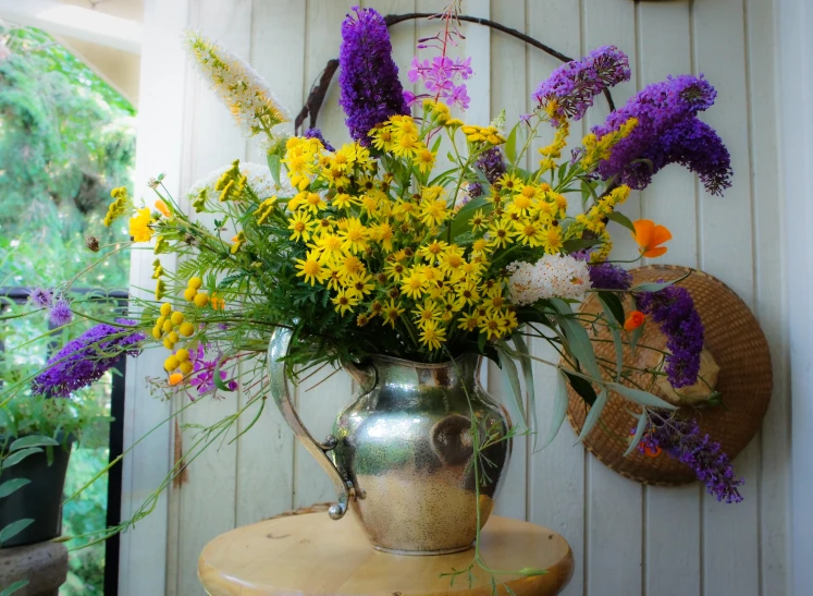 a silver pitcher that has some flowers in it