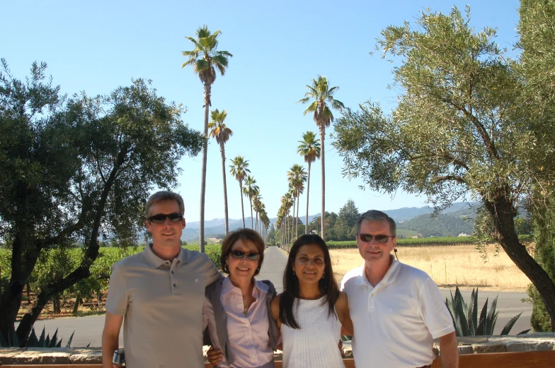 four people standing around in front of palm trees