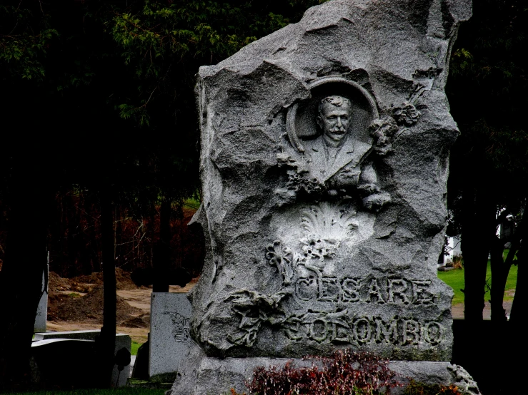 a grey monument with a picture of a man is surrounded by other gravestones