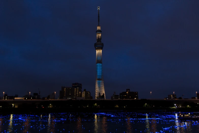 an illuminated tower on the side of the water