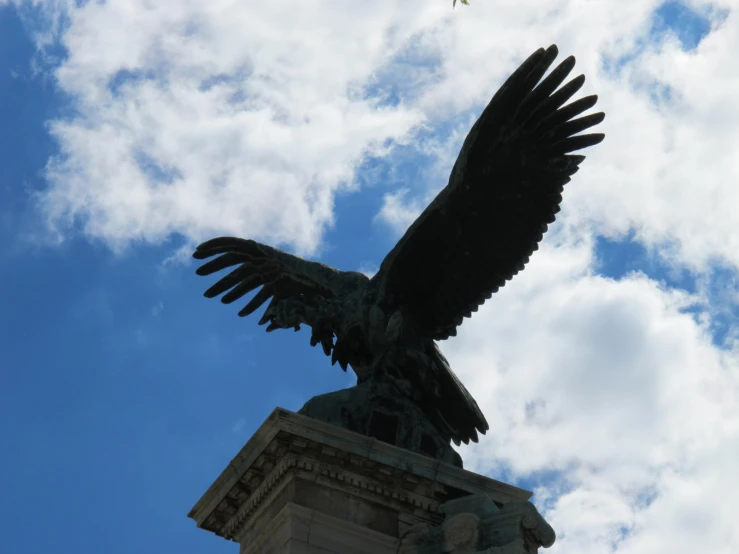 a statue of a large eagle against a cloudy blue sky