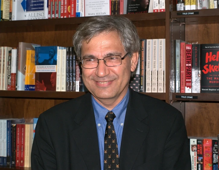 a smiling man standing in front of a book shelf
