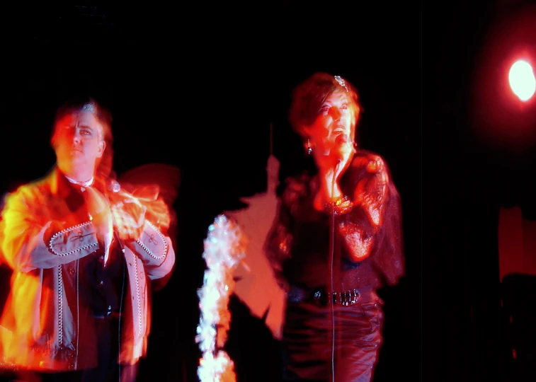 two people standing in the dark with microphones in their hands