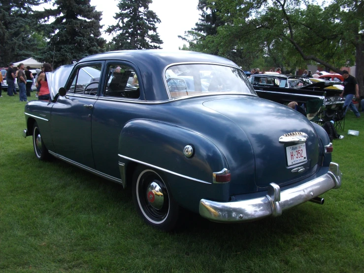 an antique car parked on the grass near people