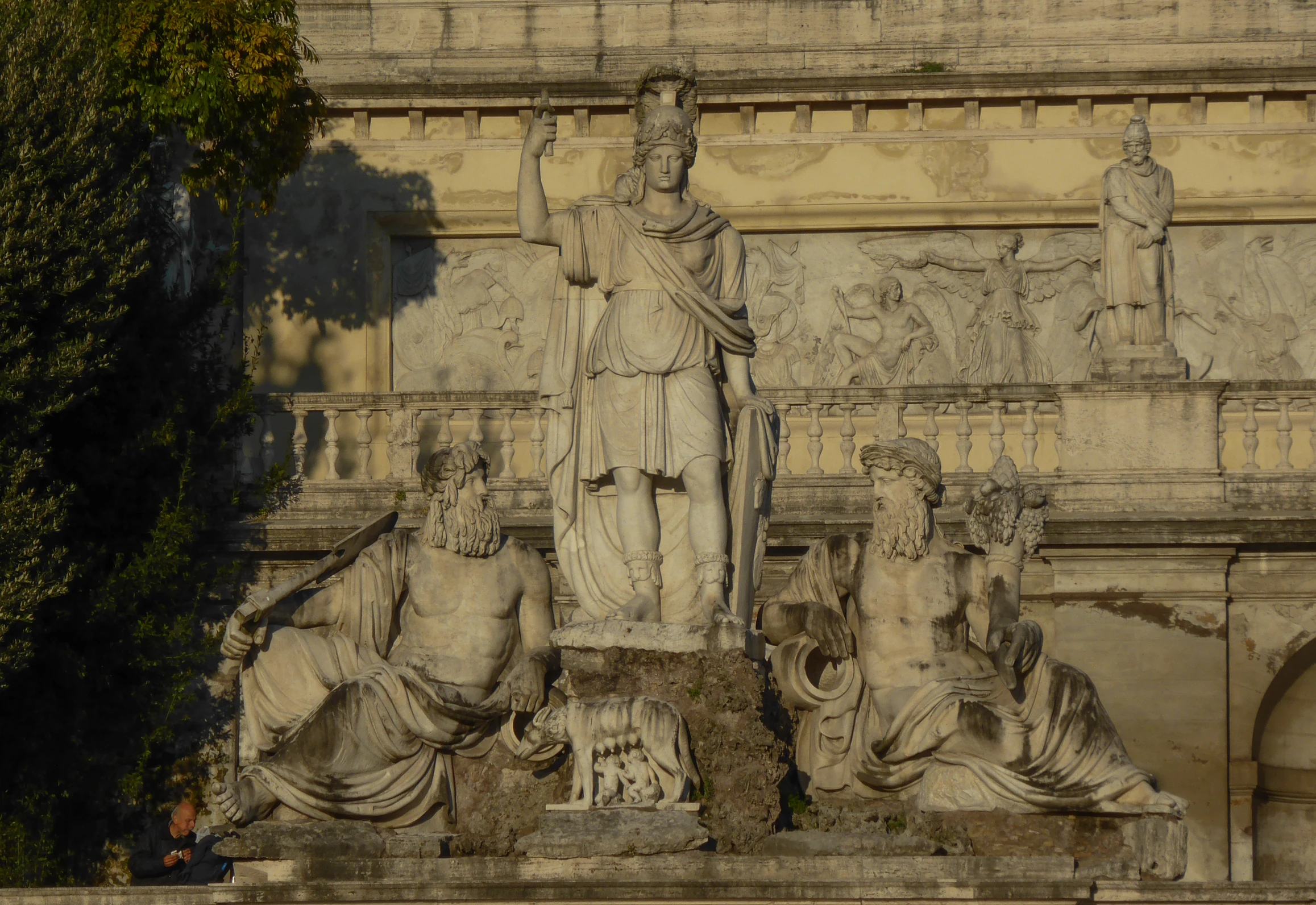 sculptures in the park sit near an intricate wall